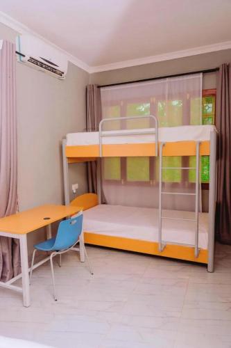 a bedroom with a bunk bed with a desk and a table at 4Luxury Hotel in Moshi