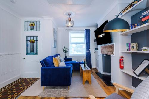 a living room with a blue couch and windows at Cozy 3-Bed Home by 53 Degrees Property, Perfect for Business & Groups! in Leek