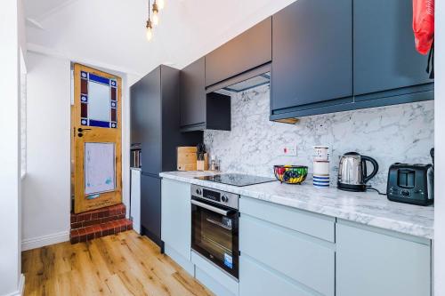 a kitchen with white counters and blue cabinets at Cozy 3-Bed Home by 53 Degrees Property, Perfect for Business & Groups! in Leek