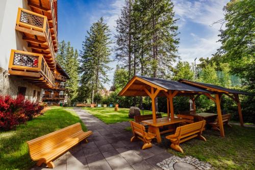 a patio with a gazebo and wooden benches at Hotel Na Skarpie in Szklarska Poręba