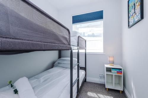 a bedroom with two bunk beds and a window at Cozy 3-Bed Home by 53 Degrees Property, Perfect for Business & Groups! in Leek