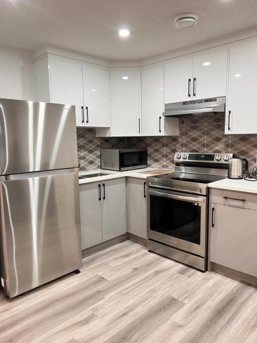 a kitchen with stainless steel appliances and white cabinets at Cozy Corner - 1 bedroom suite - 15 mins from airport in Calgary