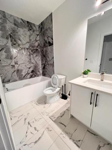 a bathroom with a toilet and a tub and a sink at Cozy Corner - 1 bedroom suite - 15 mins from airport in Calgary