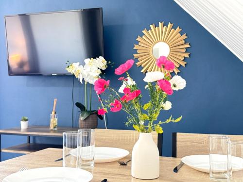 a table with a white vase with flowers in it at Appartement Platanes 6 - Proche Disney - Parking Gratuit - Meaux in Meaux