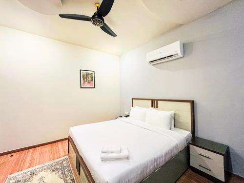a bedroom with a bed with a ceiling fan at Hotel One University Sukkur in Sukkur