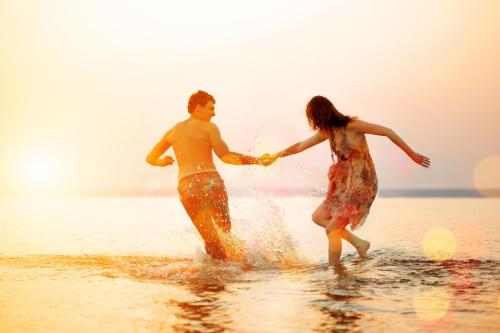 a man and a woman playing in the water on the beach at Cosy 6 Berth Caravan With Side Decking At Kessingland Beach, Suffolk Ref 90031Sv in Benacre