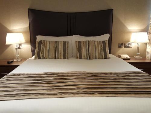 a bedroom with a large bed with two lamps and a phone at The Lodge Hotel in Coleraine
