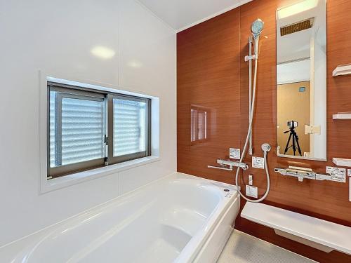 a white bathroom with a tub and a window at ulu Okinawa Resort in Motobu