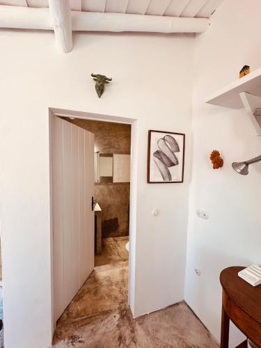 a hallway with a white door and a bathroom at Casinha do Largo - Casas da Amieira in Amieira