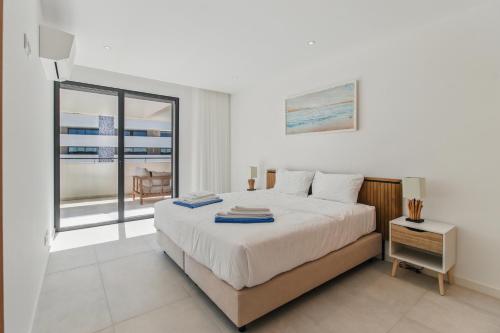 ラゴスにあるCasaLuxo New 2BR Pool Viewのベッドと大きな窓のある寝室