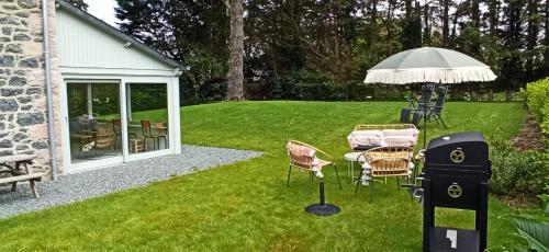 a patio with a table and chairs and an umbrella at La Maison Près des Sables in Plurien