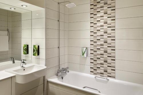 a bathroom with a sink and a tub and a mirror at Premier Inn Dublin City The Liberties in Dublin