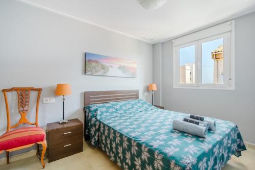a bedroom with a bed and a chair and a window at Chillout Grau de Gandia- attico para 6 personas dos banos VT-44956-V in Gandía