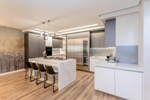 a kitchen with white cabinets and a island with bar stools at Steyn City Hotel by Saxon in Midrand