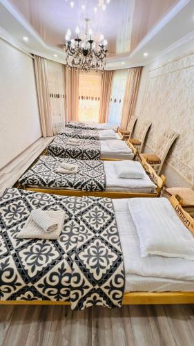 a row of beds in a room with a chandelier at Guest House Ormon in Ak-Muz