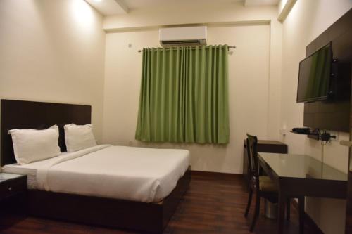 a bedroom with a bed and a green curtain at RROOMS Hotel Riddhi Grand in Lucknow