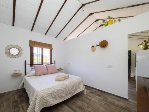 a bedroom with a bed with white walls and wooden floors at Cubo's Casa Rural Jaramago in Yunquera
