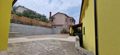 an alley with a yellow building and a fence at Sunce 3 in Vrbnik