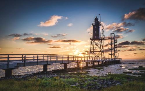 a lighthouse on a pier next to the water at Küstenkind Dorum mit Sauna und Balkon - Hunde willkommen in Dorum