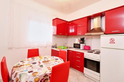 een keuken met rode kasten en een tafel met rode stoelen bij Apartment Opatija 365, steps from the sea & city center, free street parking in Opatija