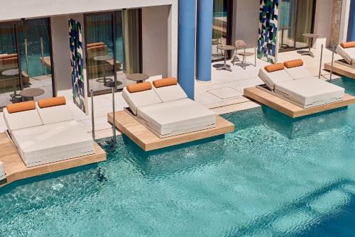 a swimming pool with two beds in the water at Paralos Kosta Alímia in Hersonissos