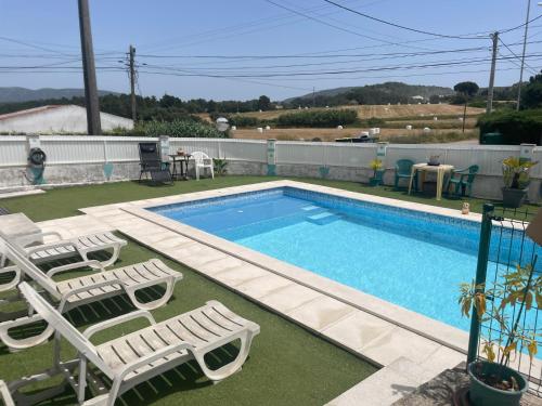 a swimming pool with two lawn chairs and a table at Casa Vila Sao & Pompeia in Sesimbra