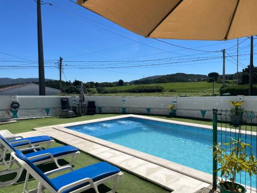 a swimming pool with two chairs and an umbrella at Casa Vila Sao & Pompeia in Sesimbra