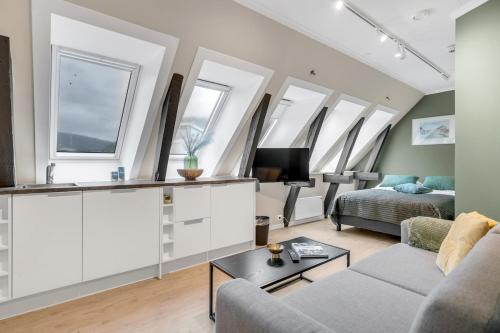 Una sala de estar con un sofá y un televisor y ventanas. en North Estate Studio Center 44, en Tromsø