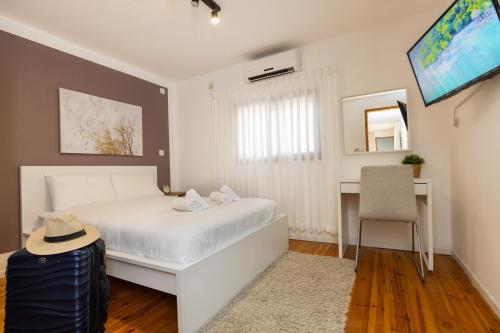 a bedroom with a white bed and a desk at אלומה- בוטיק בטבע in Sheʼar Yashuv