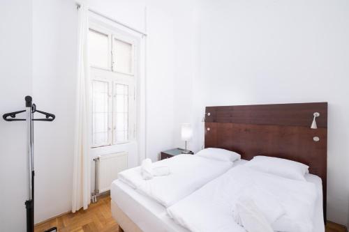 a bedroom with a large white bed with a wooden headboard at City Hotel Matyas in Budapest