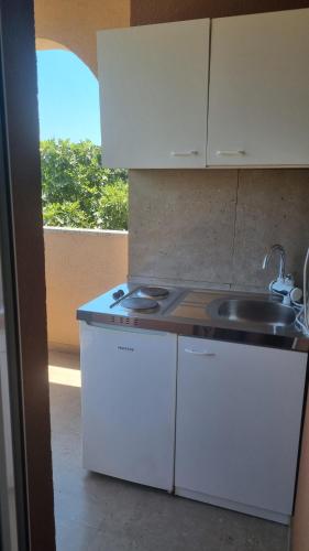 a kitchen with white cabinets and a sink and a window at Lavanda Apartments in Pakoštane
