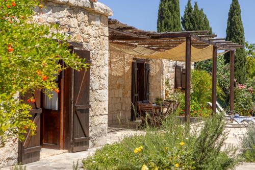 a stone house with a pergola in a garden at Simeon Estate in Droushia
