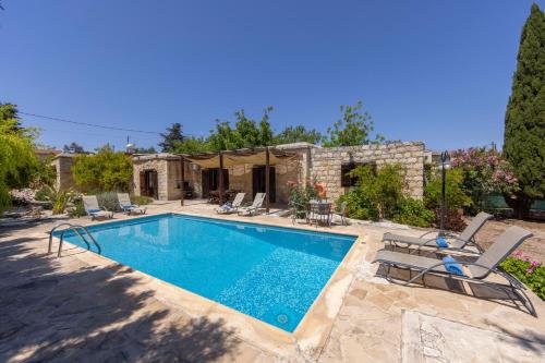a swimming pool with chairs and a house at Simeon Estate in Droushia