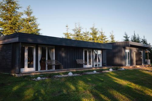 a small black house on a grass field at Vila Skodupė 