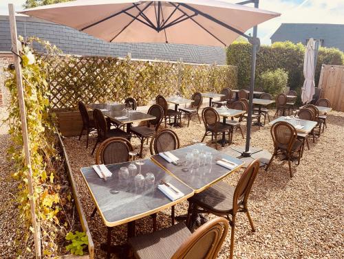 a group of tables and chairs with an umbrella at Le Coq Hardi in Blangy-le-Château