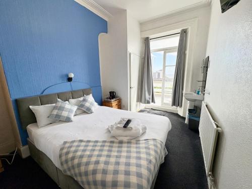 a bedroom with a bed with a blue wall at Savoy Hotel in Weston-super-Mare