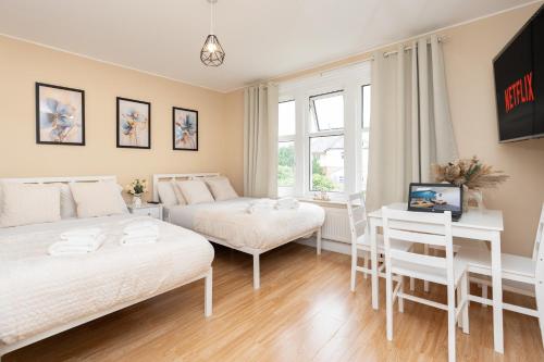 a bedroom with two beds and a desk and a tv at Open Mind Property - Cozy Studio Flat in Bournemouth