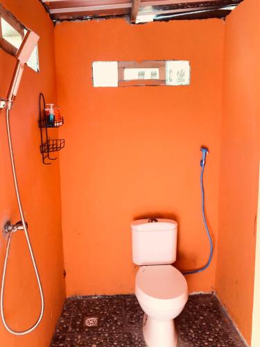 an orange bathroom with a toilet and a shower at Pondok Sedi Bungalow in Labuhancari