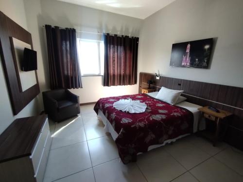 a bedroom with a bed and a chair and a window at Miotto Executive Hotel in Navegantes
