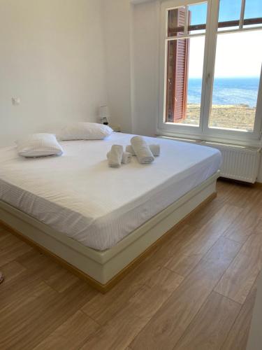 a bedroom with a bed with white sheets and windows at Artemi in Andros