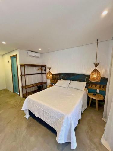 a bedroom with a large white bed and two lights at Jaguarype Bangalôs in Fortim