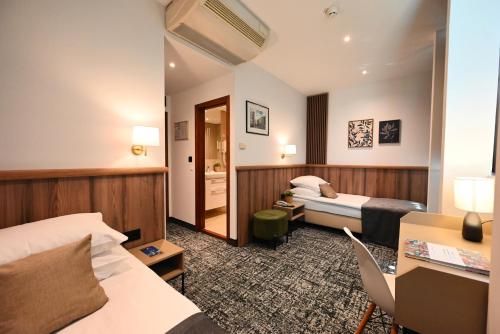 a hotel room with two beds and a desk at Hotel Central in Zagreb