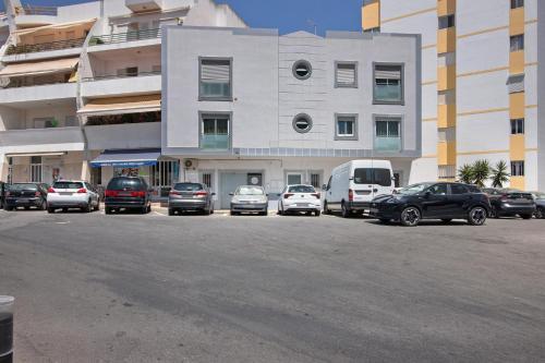 a parking lot with cars parked in front of a building at Refúgio Estrela do Mar in Quarteira