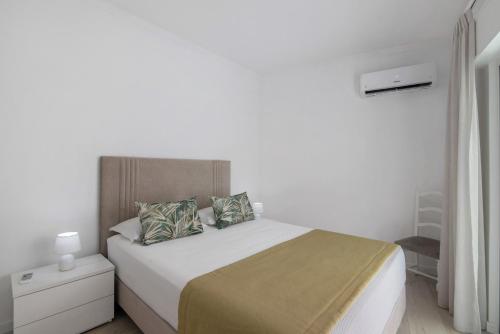 a white bedroom with a large bed with two pillows at Refúgio Estrela do Mar in Quarteira