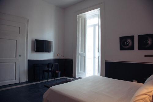 a bedroom with a bed and a tv on the wall at Altoledo Rooms and Suite in Naples