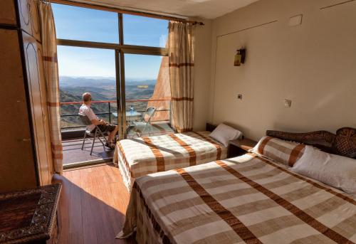 a man sitting in a chair in a hotel room with two beds at Panoramic View Hotel in Lalībela