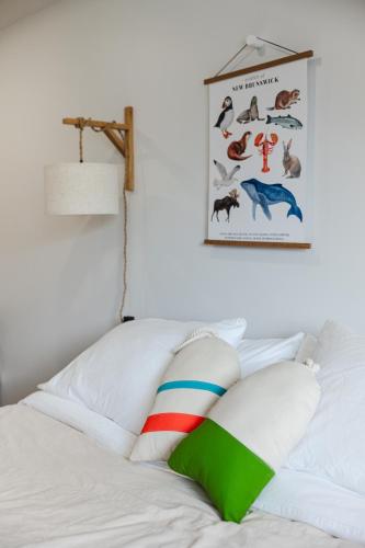 a white bed with a colorful pillow on top of it at Homeport Suites & Residences in Lords Cove 
