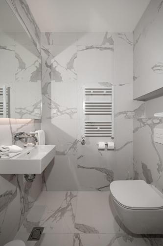 a white bathroom with a toilet and a sink at Petram Resort & Residences in Savudrija