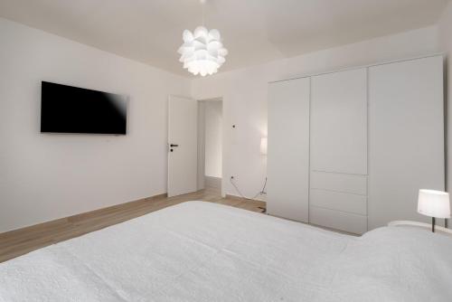 a white bedroom with a bed and a tv at Villa Ventana with terrace and BBQ in Savudrija