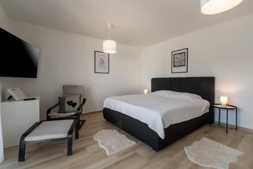 a bedroom with a bed and a chair and a tv at Villa Ventana with terrace and BBQ in Savudrija